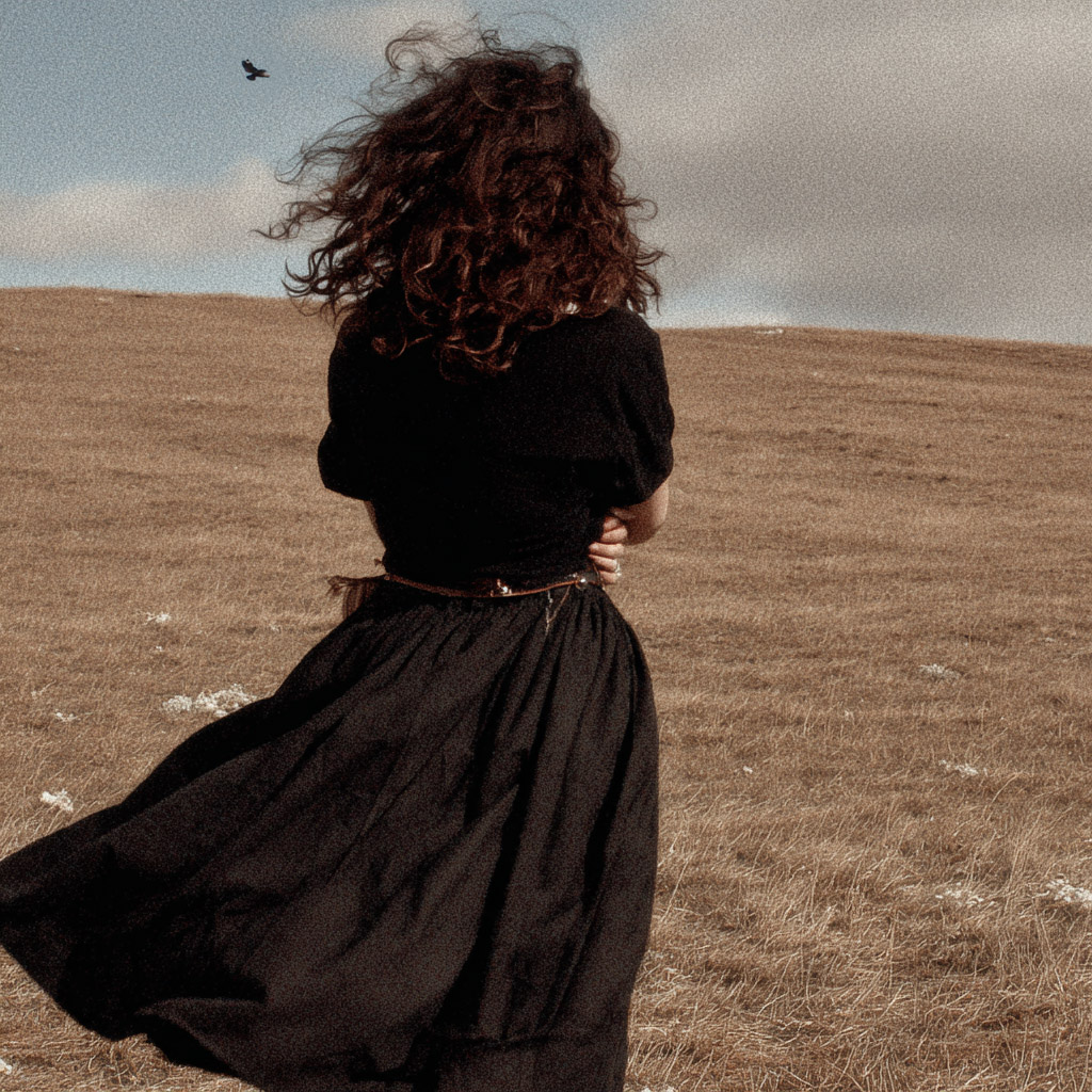 woman in a field looking up at a buzzard in the sky